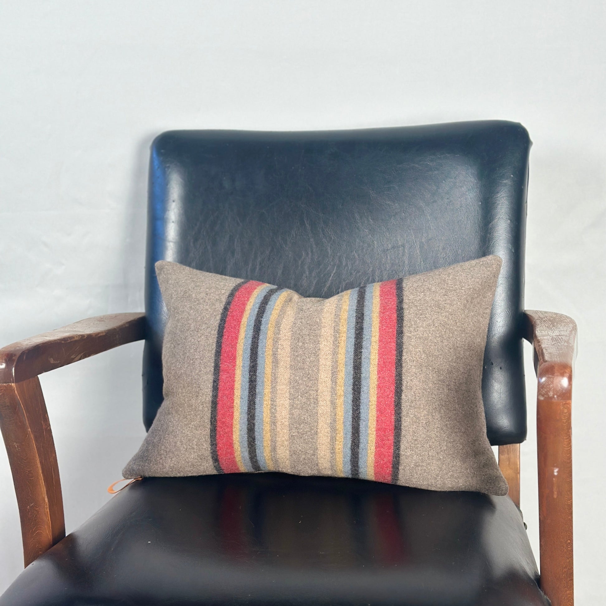 Striped pillow on a black leather chair against a white wall