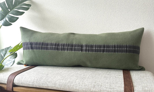 Green pillow with a long gray stripe on a bench