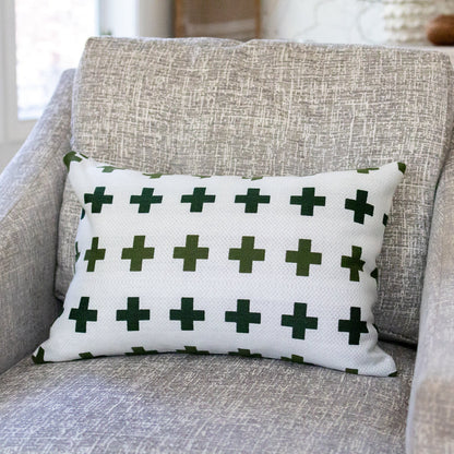 White pillow with green crosses on a gray armchair