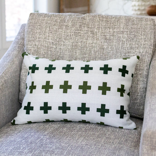 White pillow with green crosses on a gray armchair