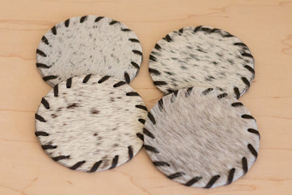 Four circular coasters with a speckled pattern on a wooden surface