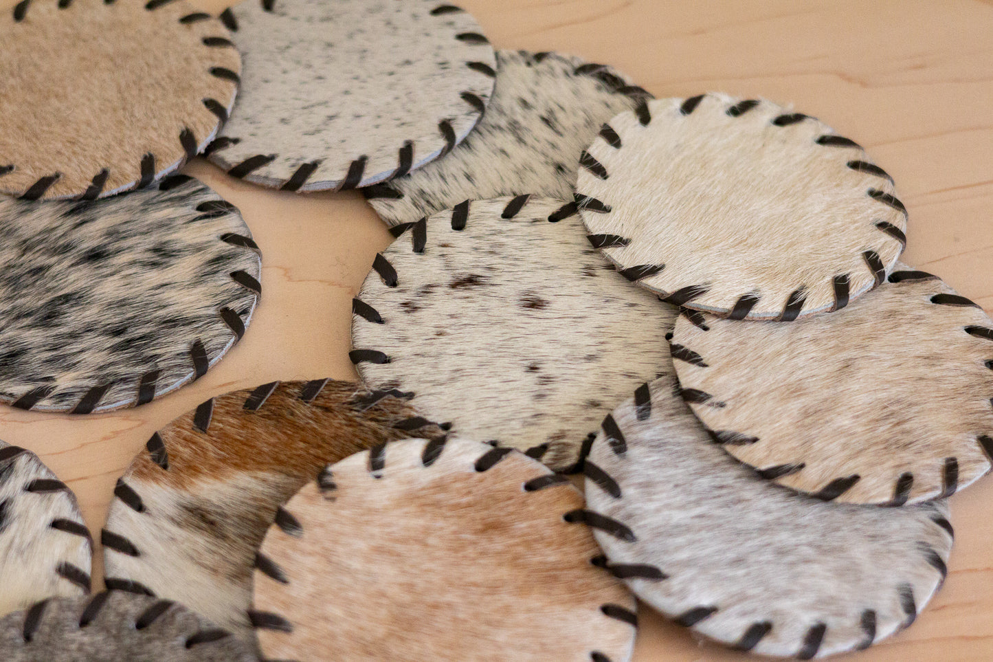 Round leather coasters with natural fur texture on a wooden surface