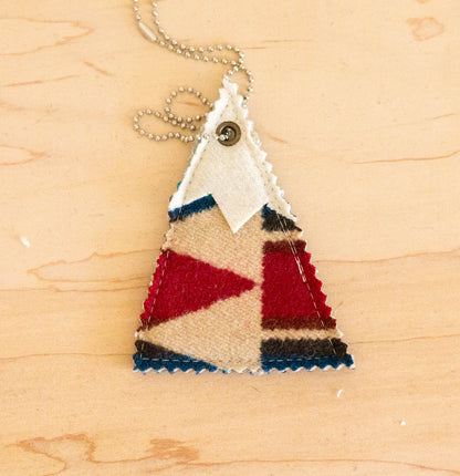 Triangular pendant with red, blue, and beige pattern on a wooden surface