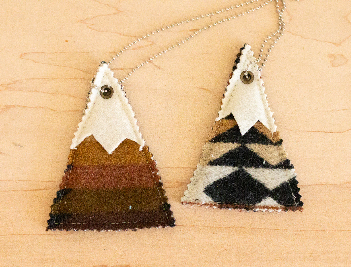 Two mountain-shaped air fresheners on a wooden surface