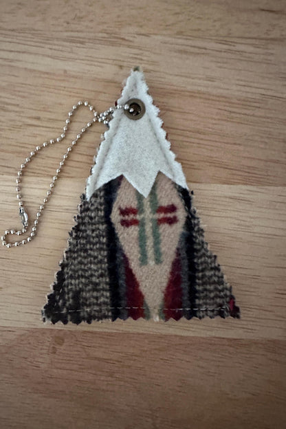 Triangular wool air freshener with mountain design on a wooden surface