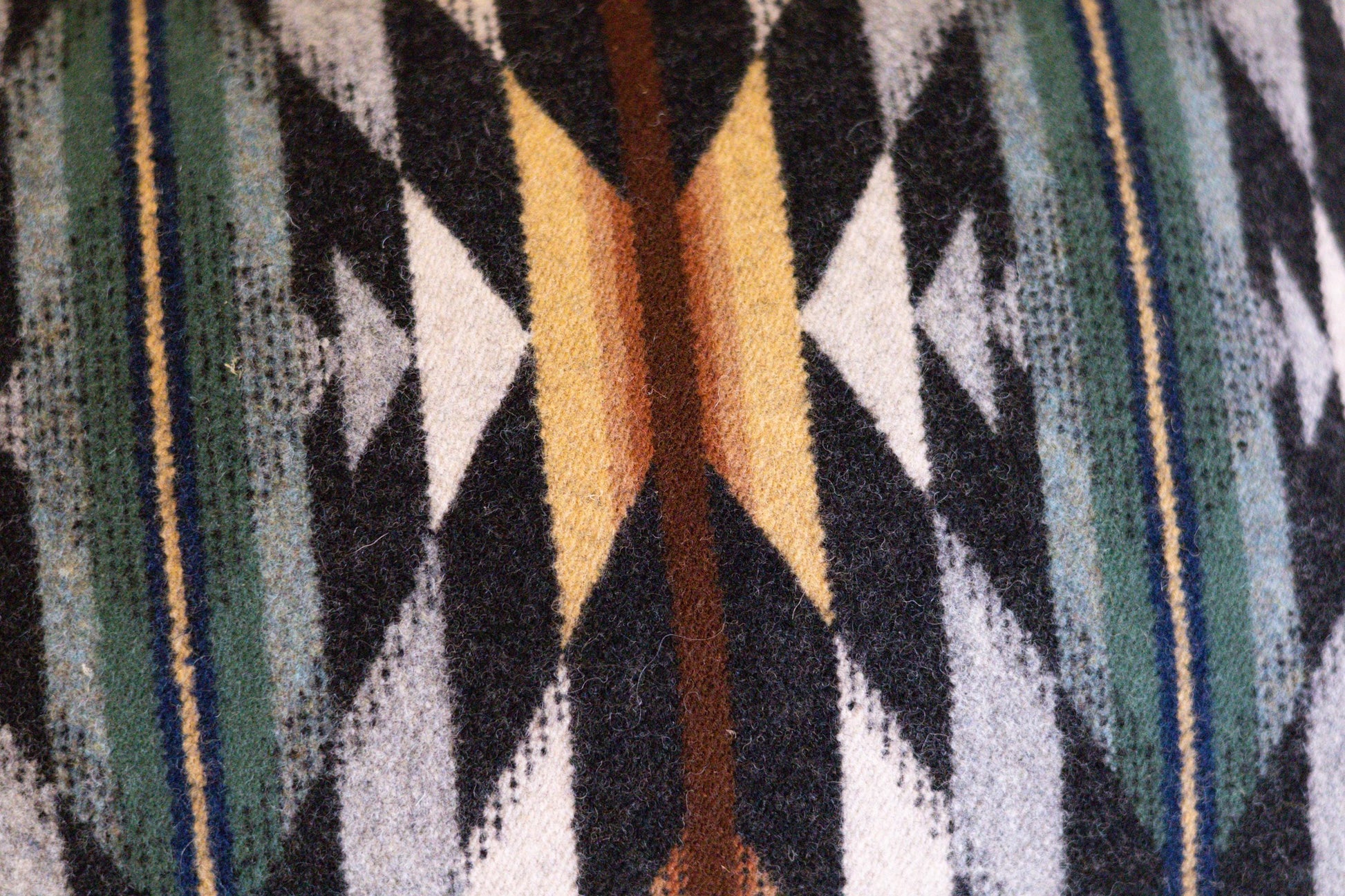 Close-up of a patterned fabric with geometric design in black, yellow, and blue.