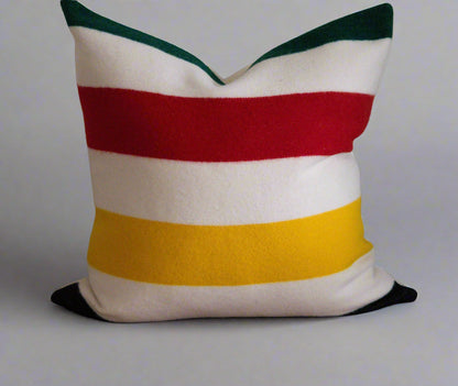 Striped pillow with red, yellow, and green on a brown surface.