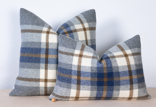 Two plaid pillows in blue, gray, and cream on a light background
