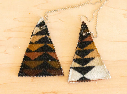 Two triangular air fresheners with zigzag pattern on a wooden surface