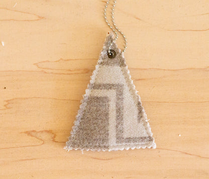 Triangular pendant with mountain design on a wooden surface