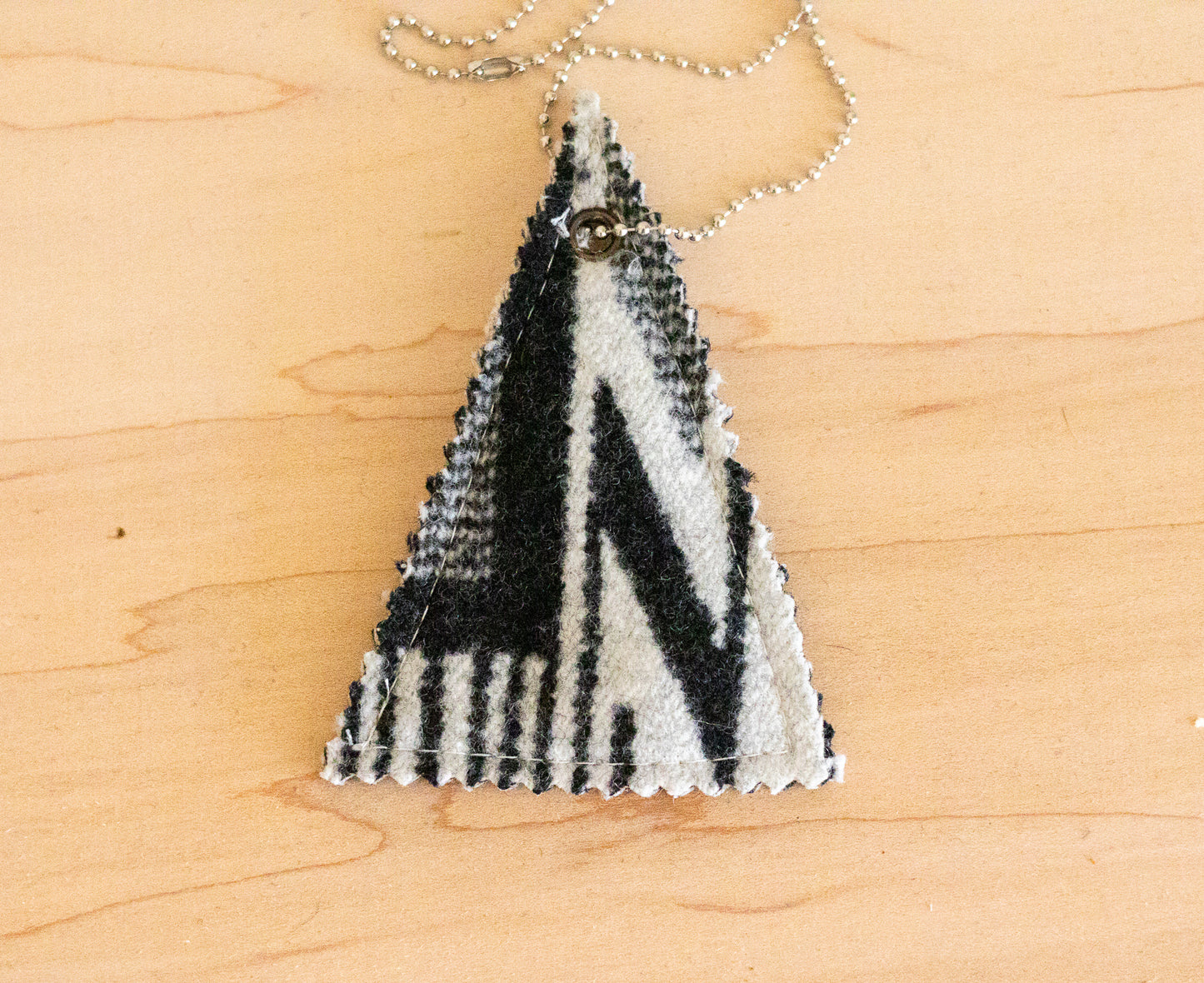 Triangular pendant with black and white pattern on a wooden surface
