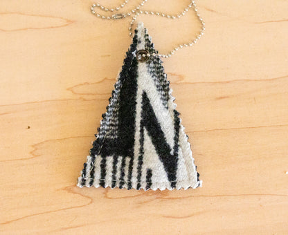 Triangular pendant with black and white pattern on a wooden surface