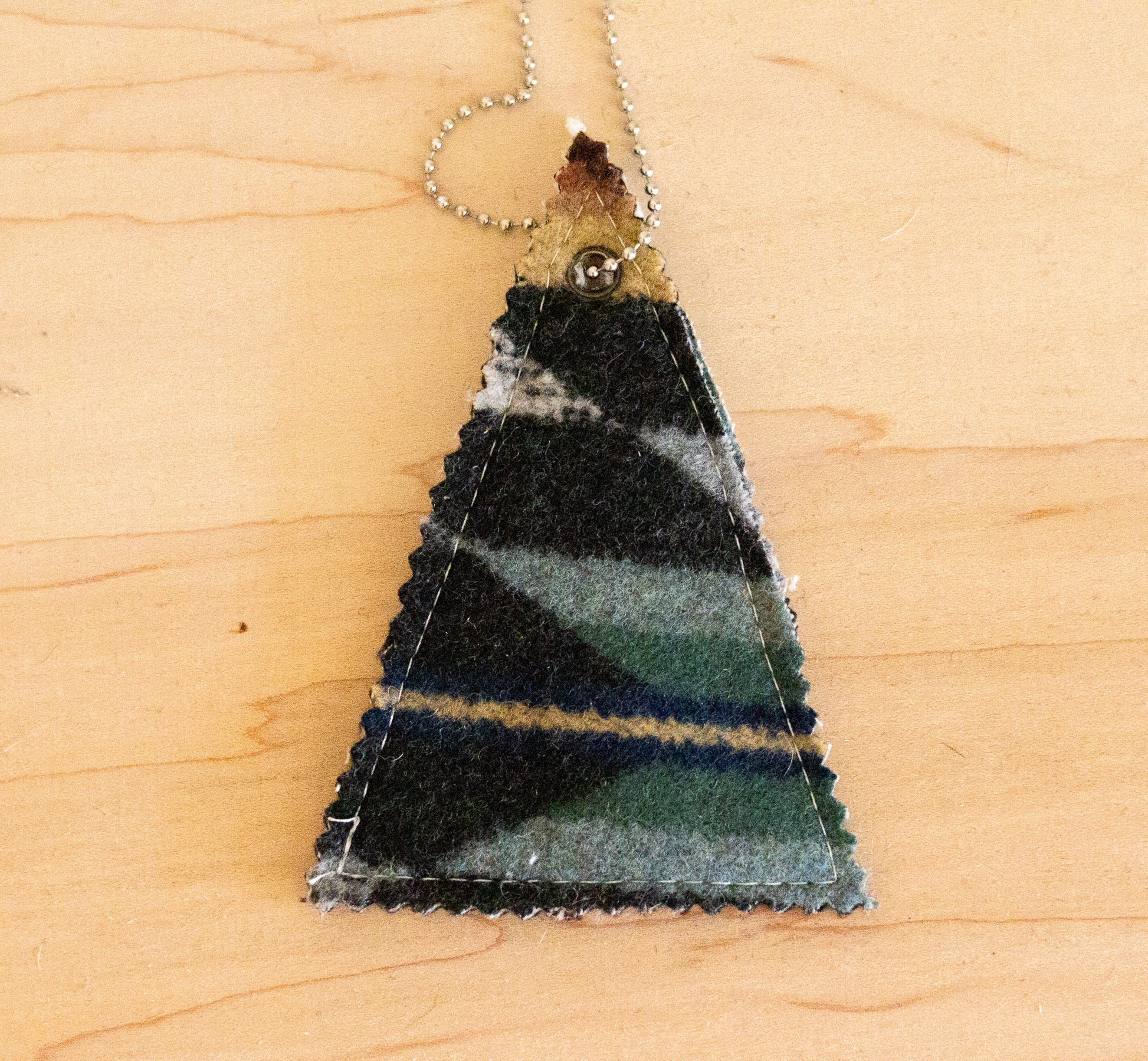 Triangular pendant with striped pattern on a wooden surface