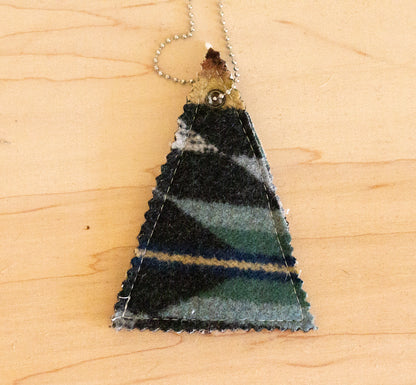 Triangular pendant with striped pattern on a wooden surface
