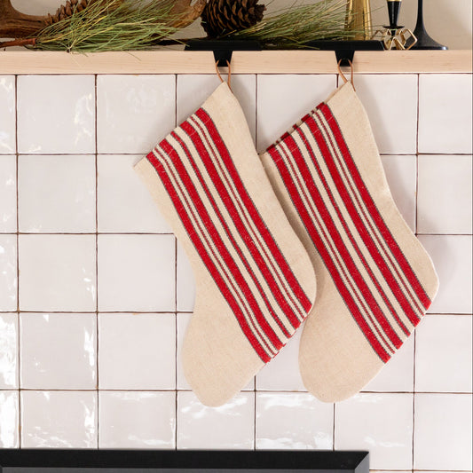 Red and white striped stockings hanging on a tiled wall.