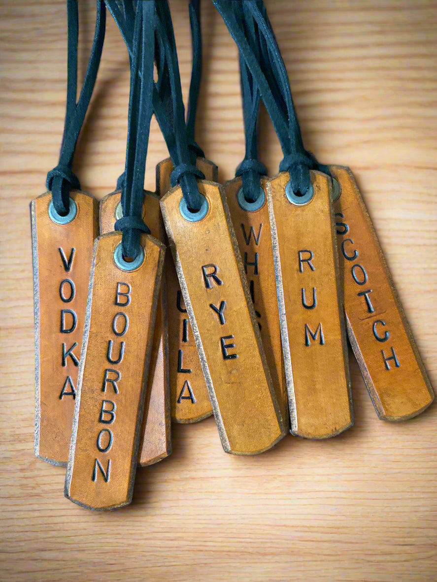 Set of leather tags with alcohol names on a dark wooden surface