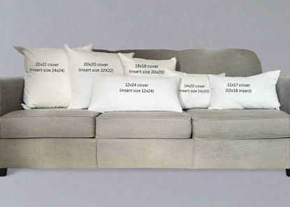 Gray sofa with decorative pillows displaying measurements in a living room.