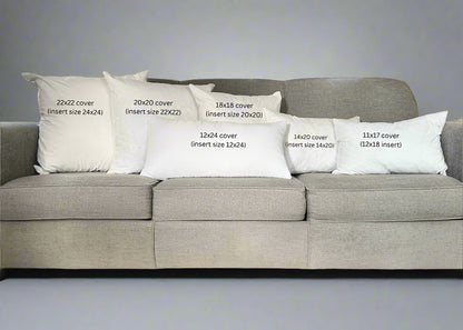 Gray sofa with decorative pillows displaying measurements in a living room.