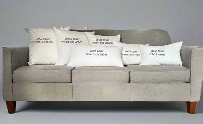 Gray sofa with decorative pillows displaying measurements in a living room setting.