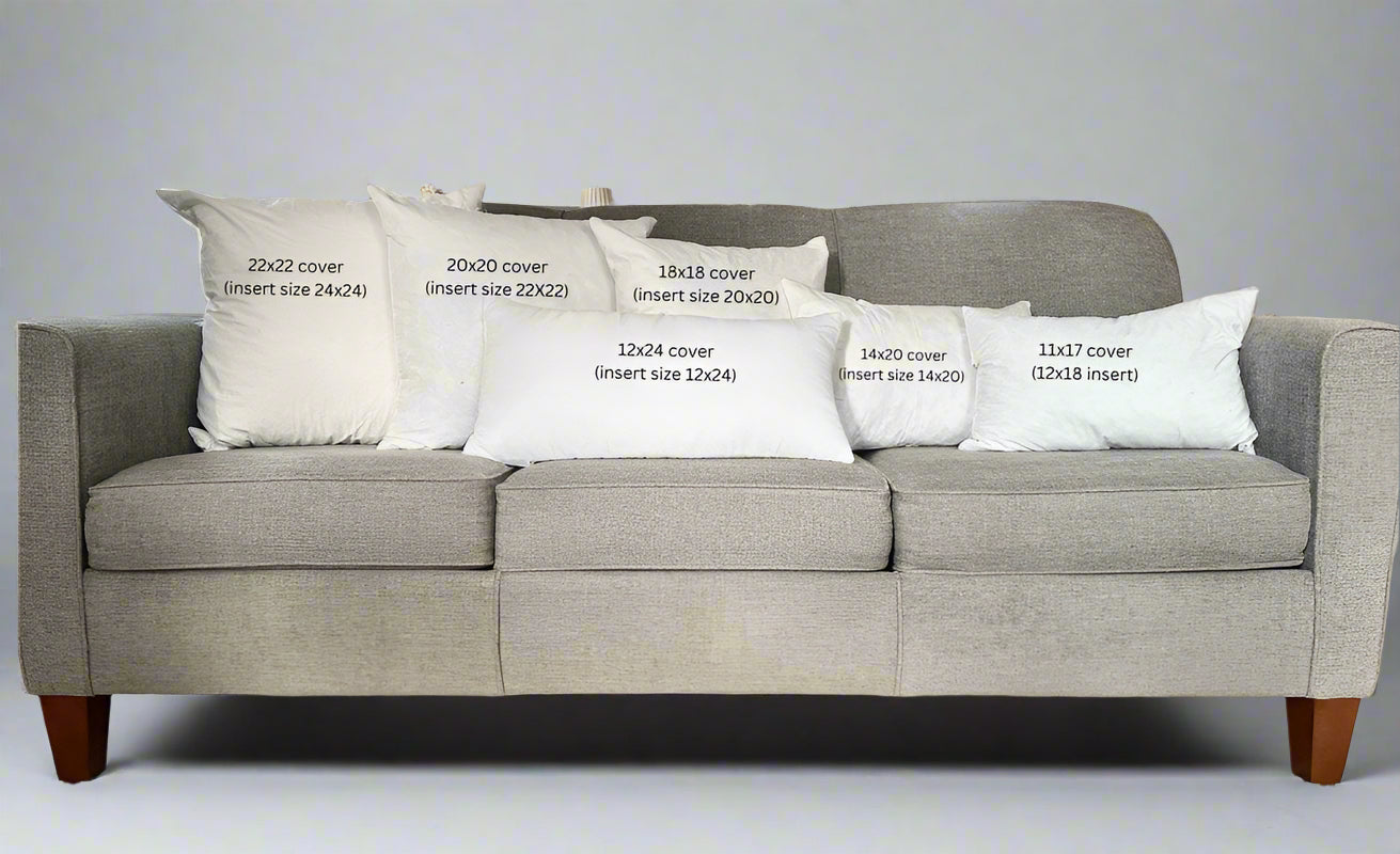 Gray sofa with decorative pillows displaying measurements in a living room setting.