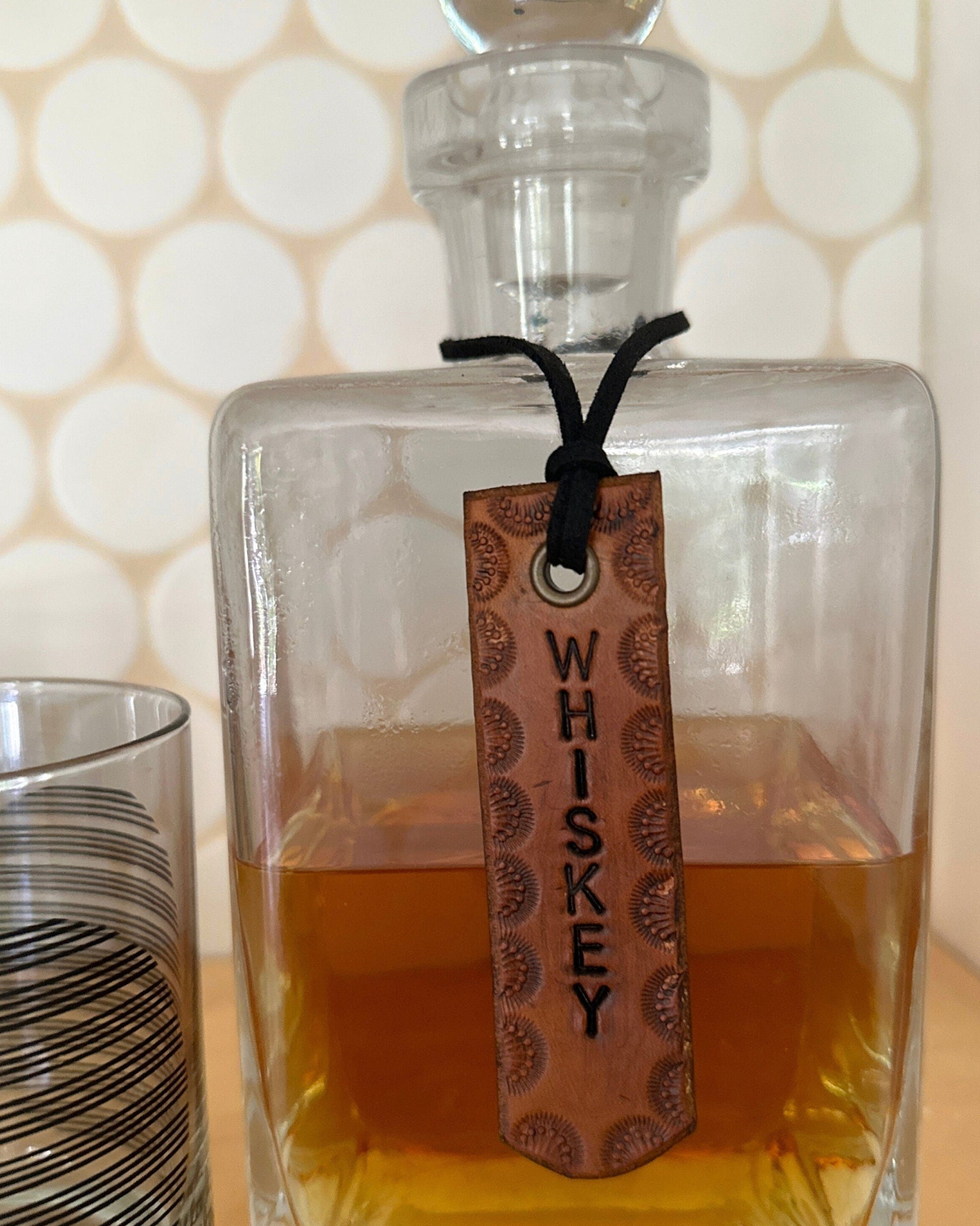 Glass whiskey decanter with a wooden tag labeled 'Whiskey' on a light background