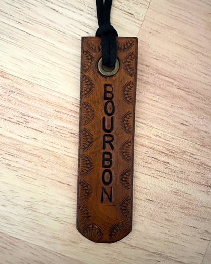 leather tag with 'Bourbon' engraving on a light wooden surface