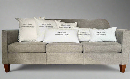Gray sofa with decorative pillows and measurements printed on them in a living room setting.