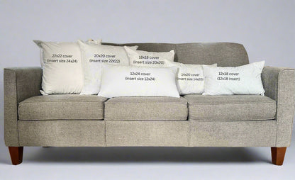 Gray sofa with decorative pillows and measurements printed on them in a living room setting.