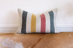 Striped pillow on a worn leather couch with a white wall background