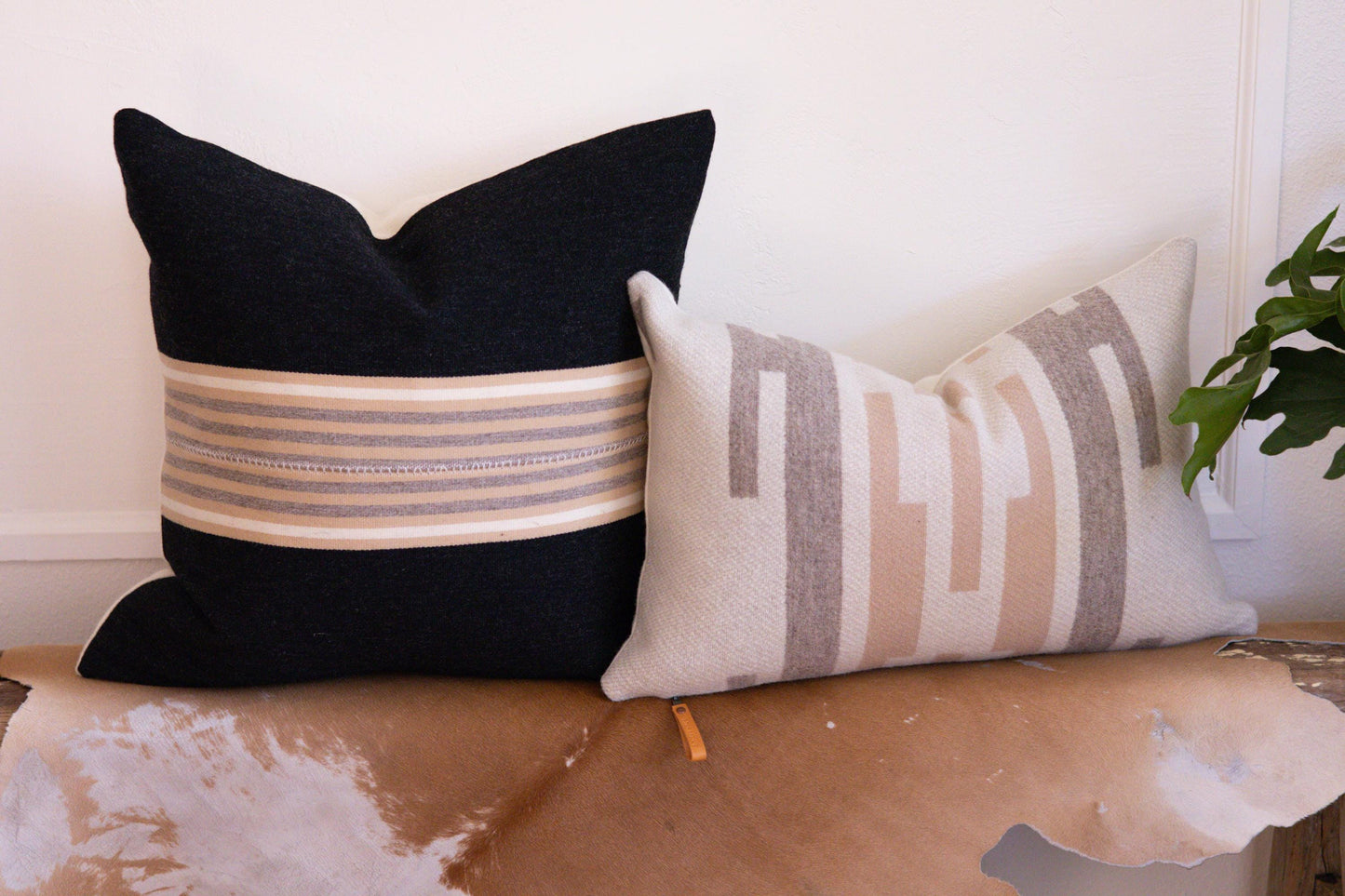 Two decorative pillows on a surface with a neutral background