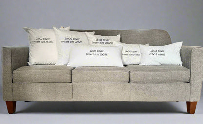 Gray sofa with decorative pillows labeled for size on a carpeted floor.