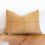 Beige pillow with black grid pattern on a beige surface
