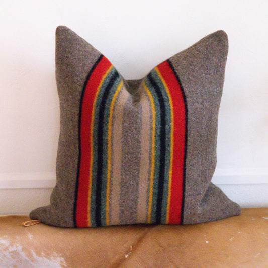 Striped pillow with brown, red, blue, and yellow colors on a beige surface.