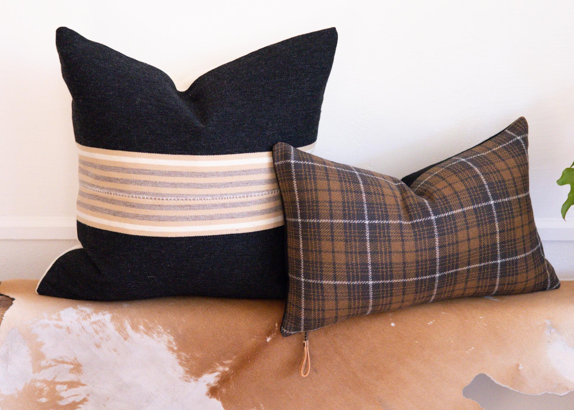 Two decorative pillows on a textured surface with a neutral background