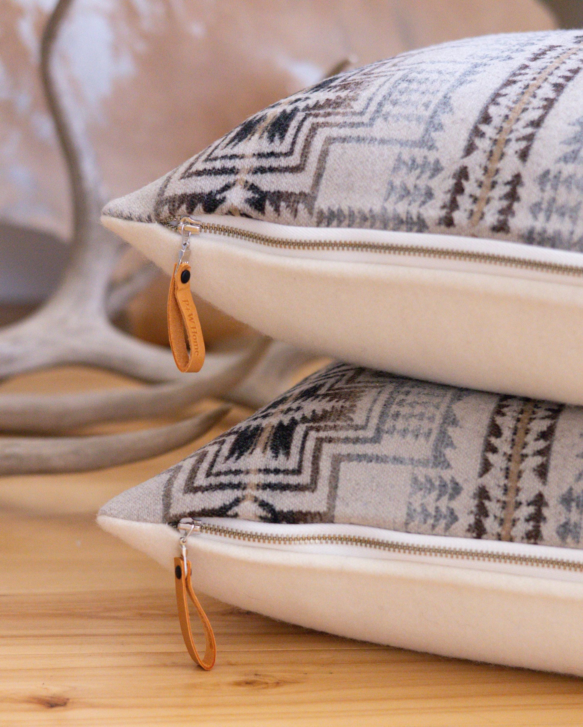 Two patterned pillows with zipper closures on a wooden surface.