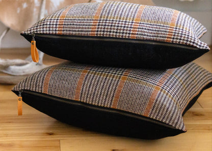 Two plaid cushions with black accents on a wooden floor.