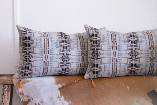 Two patterned pillows on a wooden surface with a white background