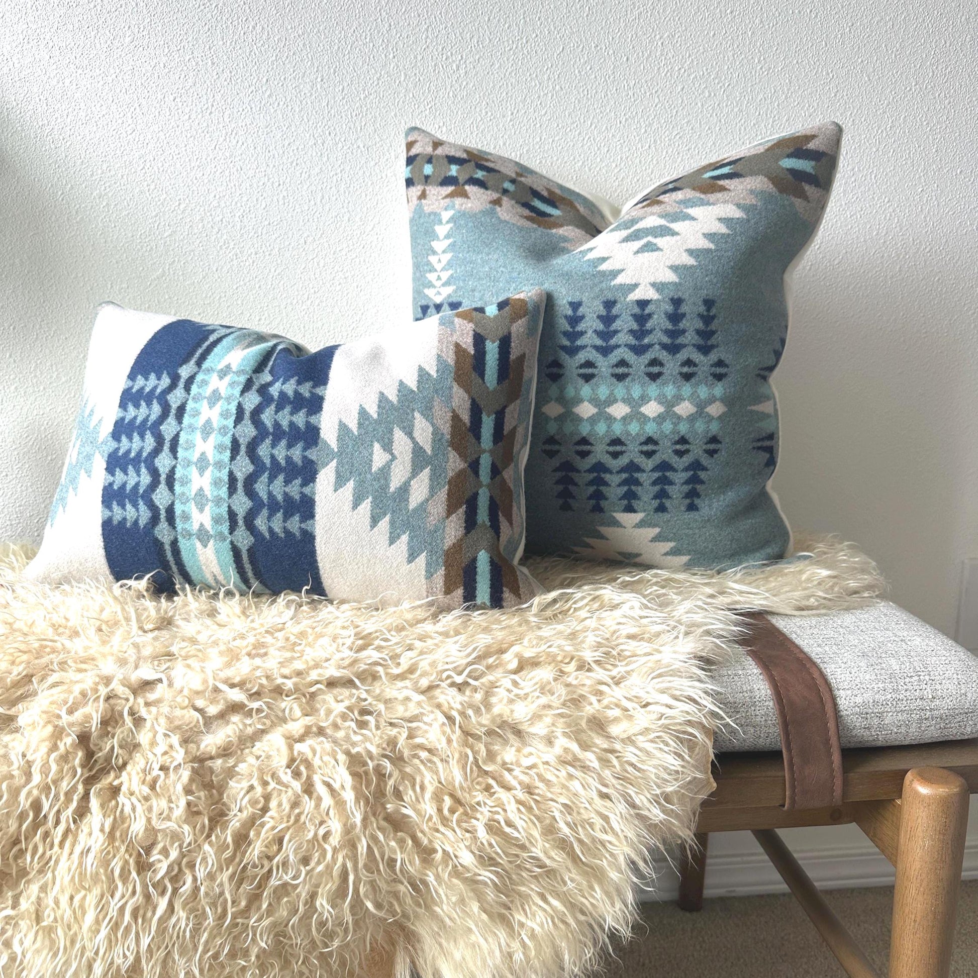 Decorative pillows with geometric patterns on a bench against a white wall