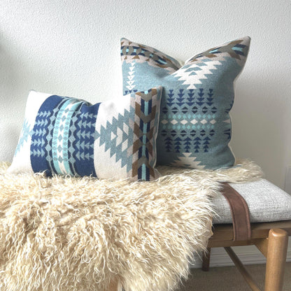 Decorative pillows with geometric patterns on a bench against a white wall