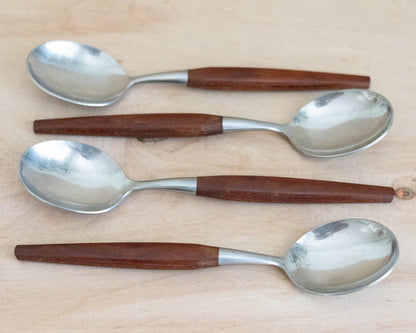 Four spoons with wooden handles on a light wood surface