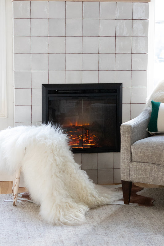 Living room with a fireplace, white rug, and gray chair.