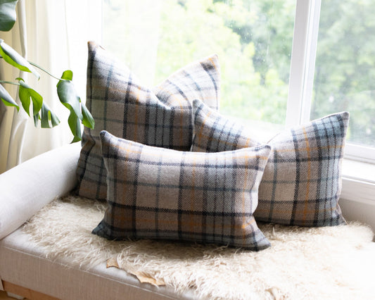 Plaid cushions on a sofa by a window with natural light
