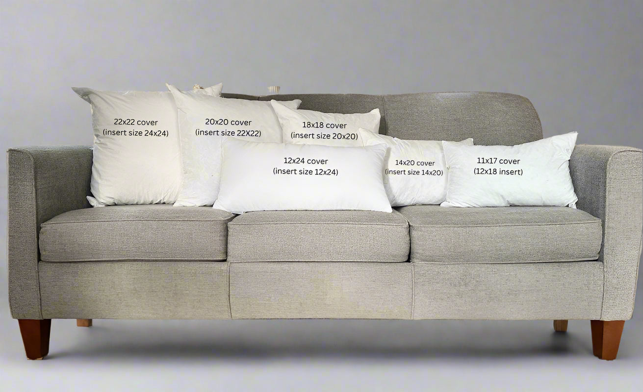 Gray sofa with decorative pillows displaying measurements in a studio setting.