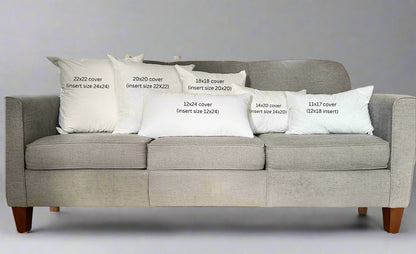 Gray sofa with decorative pillows displaying measurements in a studio setting.