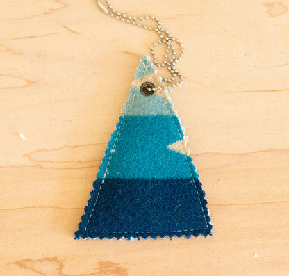 Triangular pendant with blue gradient on a wooden surface