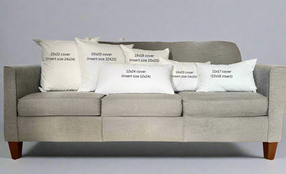 Gray sofa with decorative pillows displaying measurements in a living room setting.